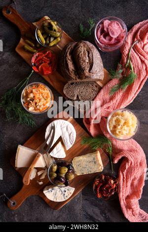 Gesunde probiotische Käseplatte serviert mit Kimchi, Sauerteigbrot mit dunkler Färbung und fermentiertem Gemüse. Stockfoto