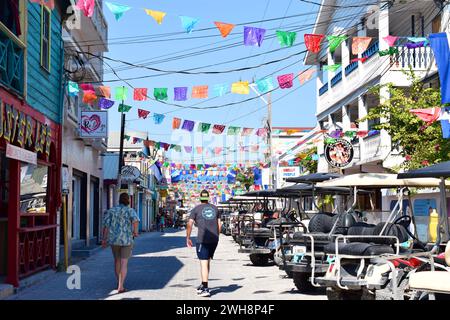 Zwei Touristen gehen die First Street, alias Barrier Reef Drive, in San Pedro Town, Ambergris Caye, Belize. Stockfoto