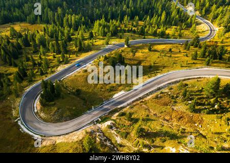 Das Auto fährt auf kurviger Asphaltstraße, die sich entlang eines großen Waldes mit immergrünen Nadelbäumen schlängelt. Serpentine Freeway über Forstberge aus der Vogelperspektive Stockfoto