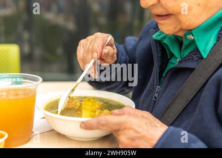 Eine nicht erkennbare Seniorin, die eine Suppe am Tisch hat Stockfoto