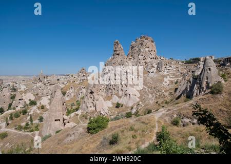 Allgemeiner Blick auf das Höhlendorf Uchisar in Kappadokien mit seiner aus vulkanischem Felsen gemeißelten Burg vor einem blauen Himmel, horizontal Stockfoto