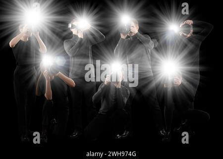 Gruppe von Fotografen mit Kameras auf schwarzem Hintergrund. Paparazzi machen Bilder mit Blitzen Stockfoto