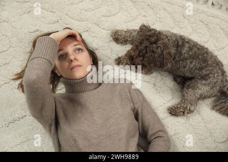 Traurige junge Frau und ihr Hund liegen zu Hause auf dem Boden Stockfoto