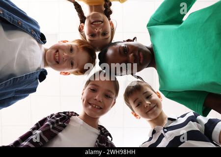 Glückliche Kinder, die sich in der Schule drängen, von unten Stockfoto