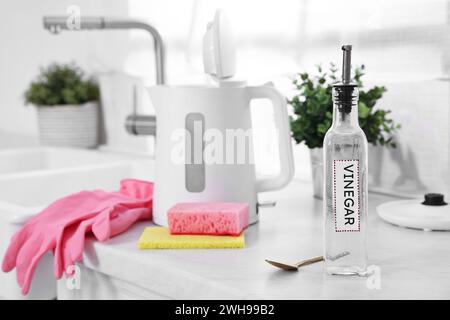 Reinigen des elektrischen Wasserkochers. Flasche Essig, Gummihandschuhe, Schwamm und Löffel mit Natron auf der Arbeitsplatte in der Küche Stockfoto