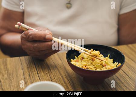 Detailaufnahme einer Frau, die Reis und Gemüse mit Essstäbchen isst Stockfoto