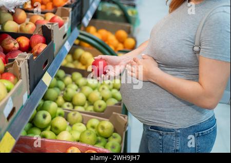 Schwangere Frau wählt Äpfel im Laden. Stockfoto