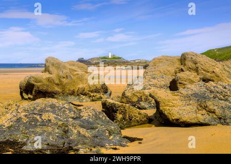 Der Leuchtturm von Godrevy und riesige Felsen, die sich bei Ebbe am Strand an einem perfekten Frühlingstag offenbaren. Stockfoto