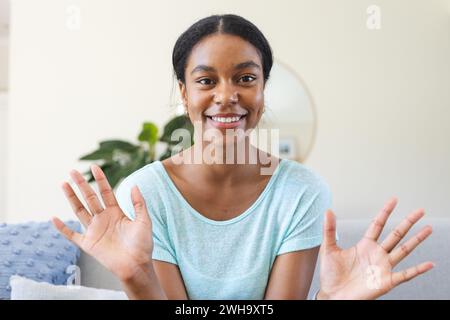 Eine junge Frau mit birassischer Rasse lächelt bei einem Videoanruf zu Hause hell Stockfoto