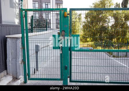 Eingangstür zum Innenhof. Metalldrahtzaun. Grüne Eingangstüren aus Metall. Die Fernbedienung zum Öffnen der Heckklappe durch Motorautomatisierung ist zu Hause Stockfoto