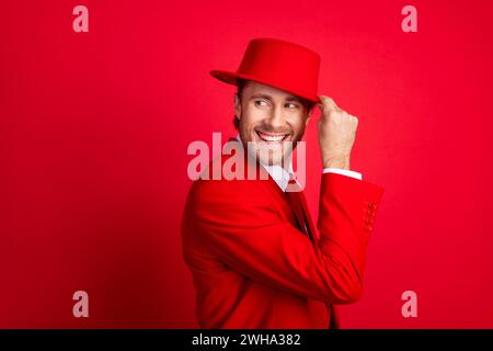 Foto-Porträt des eleganten jungen männlichen Touch-Hut-Look leerer Raum gekleidet stilvolles klassisches Kleid isoliert auf rotem Farbhintergrund Stockfoto