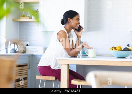 Eine junge, birassische Frau plaudert zu Hause am Telefon Stockfoto