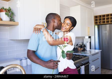 Ein junger afroamerikanischer Mann küsst eine Frau in einer Küche Stockfoto
