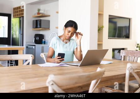 Die junge birassische Frau arbeitet von zu Hause aus und konzentriert sich auf ihren Laptop Stockfoto