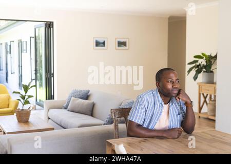 Junger afroamerikanischer Mann sitzt nachdenklich zu Hause, mit Kopierraum Stockfoto