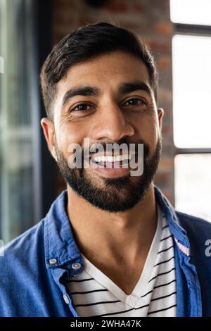 Ein junger asiatischer Mann lächelt in einem zwanglosen Business-Büro Stockfoto