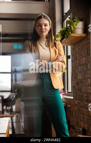 Junge kaukasische Frau steht selbstbewusst in einem zwanglosen Geschäftsbüro Stockfoto