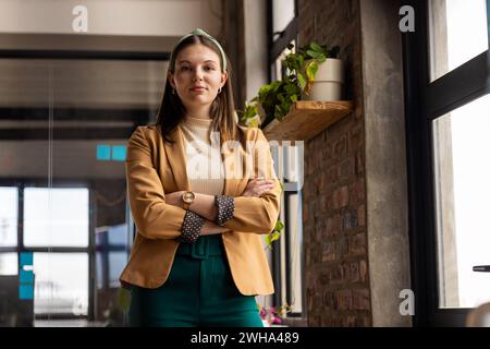 Junge kaukasische Frau steht selbstbewusst in einem zwanglosen Geschäftsbüro Stockfoto