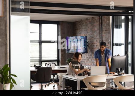 Asiatische Frau und afroamerikanischer Mann arbeiten in einem modernen Geschäftsbüro zusammen Stockfoto