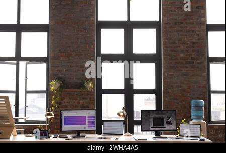 Ein modernes, zwangloses Büro mit großen Fenstern und mehreren Monitoren Stockfoto