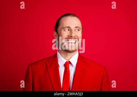 Foto-Porträt des eleganten jungen männlichen fröhlichen Ausblicks leerer Raum gekleidet stilvolle klassische Kleidung isoliert auf rotem Farbhintergrund Stockfoto