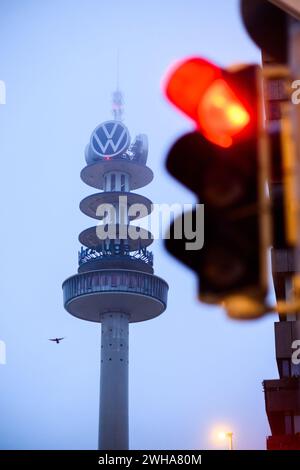 Hannover, Deutschland. Februar 2024. Eine rote Ampel leuchtet in Sichtweite des ehemaligen „Telemoritz“-Fernsehturms (auch bekannt als „VW-Turm“). Der 1959 erbaute und 141 Meter hohe Turm ist seit 2000 im Besitz von Volkswagen Nutzfahrzeugen. Medienberichten zufolge wird der Abriss des Turms in Erwägung gezogen. Quelle: Julian Stratenschulte/dpa/Alamy Live News Stockfoto