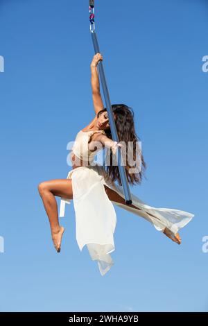 Professionelle weibliche Luftfahrerin, die draußen auf der Lufttanzstange auftritt Stockfoto