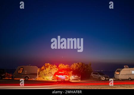 Faszinierende Langzeitaufnahmen von Campern und Kleinbussen an der Küste, die die ruhige Schönheit und gemeinsame Momente am Meer hervorheben. Stockfoto