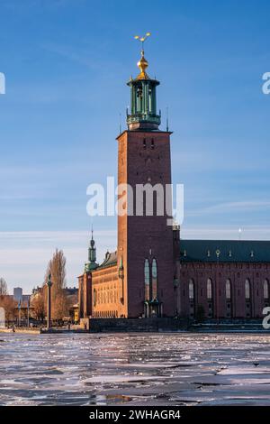 Das alte Rathaus von Stockholm im Stadtteil Kungsholmen im Winter, Eis auf dem See, blauer Himmel mit dünner Zirrusschicht. Helle Sonne. Stockfoto