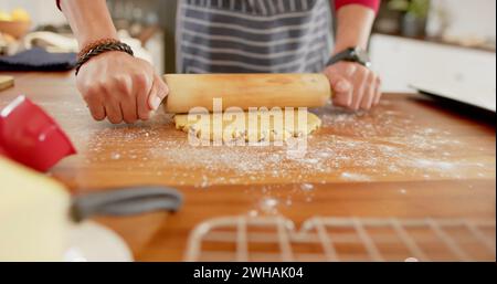 Die Person rollt den Teig auf einer Küchentheke aus Stockfoto