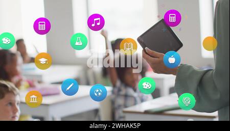 Bild von Schulsymbolen über verschiedenen Schülern und birassischen Lehrerinnen mit Tablet im Klassenzimmer Stockfoto