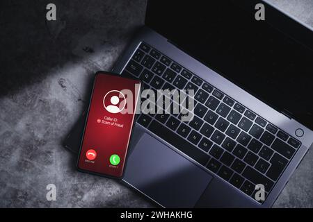 Smartphone empfängt unerwünschte Anrufe, während es sich auf dem Laptop ruht. Konzept für Spam, Betrug, Phishing und Betrug. Sicherheitstechnologie. Stockfoto