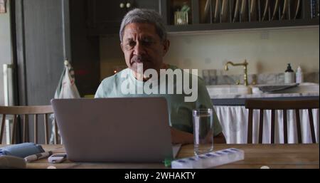 Ein hochrangiger birassischer Mann arbeitet zu Hause an einem Laptop Stockfoto