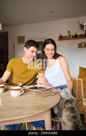 Ein Mann streichelt seinen Hund, während er mit seiner Freundin frühstückt. Stockfoto