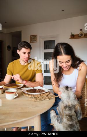 Eine Frau streichelt ihren Hund, während sie mit ihrem Freund frühstückt. Stockfoto