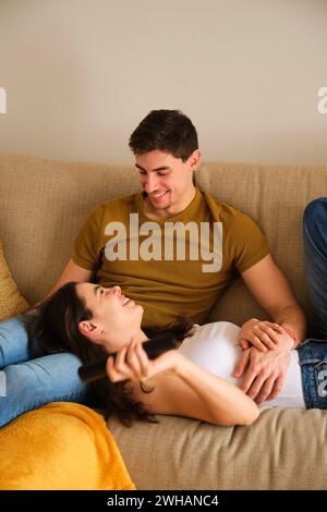 Spanisches Paar lacht zusammen auf dem Sofa. Stockfoto