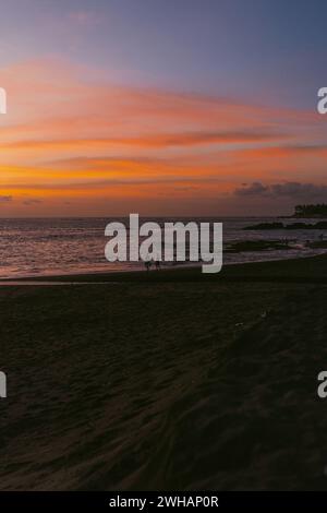 Leute bei Sonnenuntergang am Strand am Meer. Stockfoto