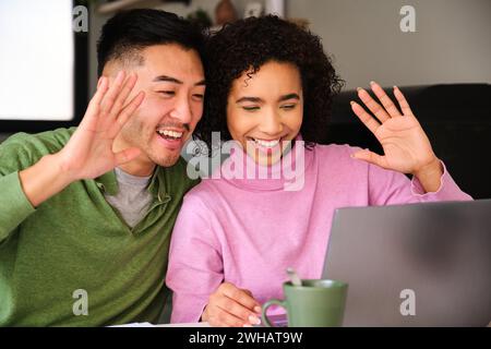 Multiethnische glückliche Paare winken bei einem Videogespräch mit Familie oder Freunden. Stockfoto