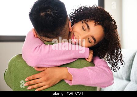 Dominikanerin umarmt ihren chinesischen Freund zu Hause. Stockfoto