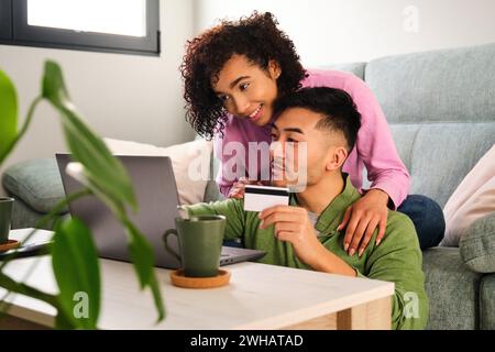 Multirassisches glückliches Paar, das online shoppt, eine Reisebuchung macht. Stockfoto