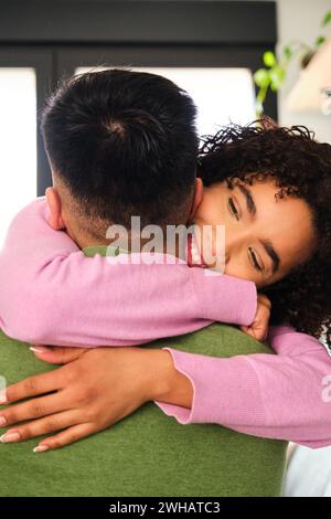 Eine lateinische Frau umarmt ihren asiatischen Freund zu Hause. Stockfoto
