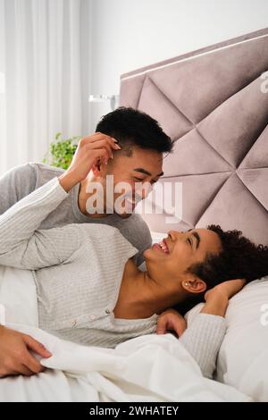 Ein romantisches Paar wacht während der Flitterwochen zusammen im Bett auf. Stockfoto
