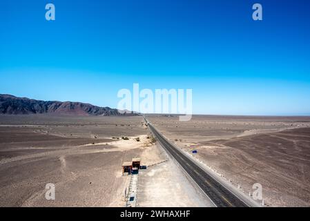 Asphaltstraße durchquert die Wüste wie eine gerade Linie aus schwarzem Teer in der braunen Wüste von Nazca Peru Stockfoto