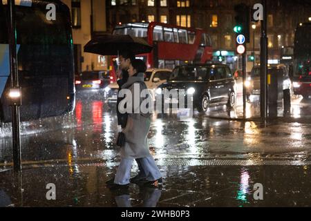 Touristen mit Regenschirmen an einer verregneten Winternacht in Aldwych, Londons Theaterviertel im West End, London, England, Großbritannien Stockfoto