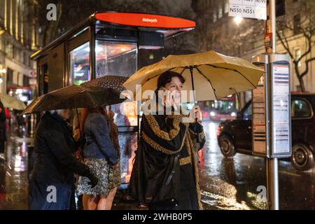 Touristen mit Regenschirmen an einer verregneten Winternacht in Aldwych, Londons Theaterviertel im West End, London, England, Großbritannien Stockfoto