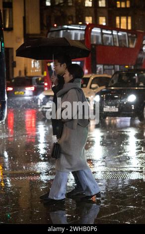 Touristen mit Regenschirmen an einer verregneten Winternacht in Aldwych, Londons Theaterviertel im West End, London, England, Großbritannien Stockfoto