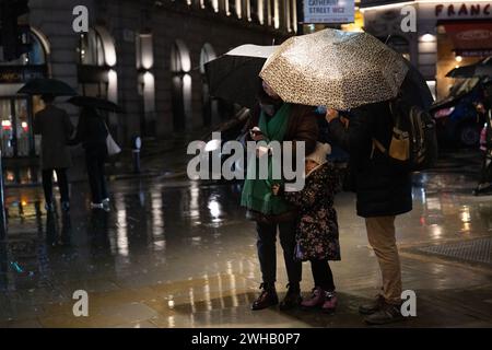 Touristen mit Regenschirmen an einer verregneten Winternacht in Aldwych, Londons Theaterviertel im West End, London, England, Großbritannien Stockfoto