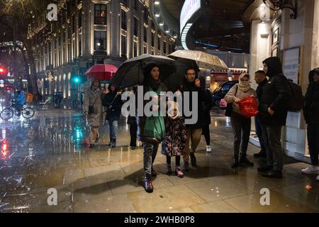 Touristen mit Regenschirmen an einer verregneten Winternacht in Aldwych, Londons Theaterviertel im West End, London, England, Großbritannien Stockfoto