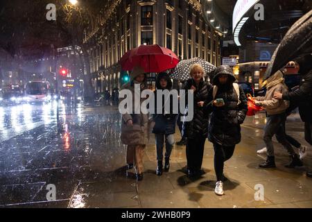 Touristen mit Regenschirmen an einer verregneten Winternacht in Aldwych, Londons Theaterviertel im West End, London, England, Großbritannien Stockfoto