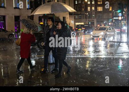 Touristen mit Regenschirmen an einer verregneten Winternacht in Aldwych, Londons Theaterviertel im West End, London, England, Großbritannien Stockfoto